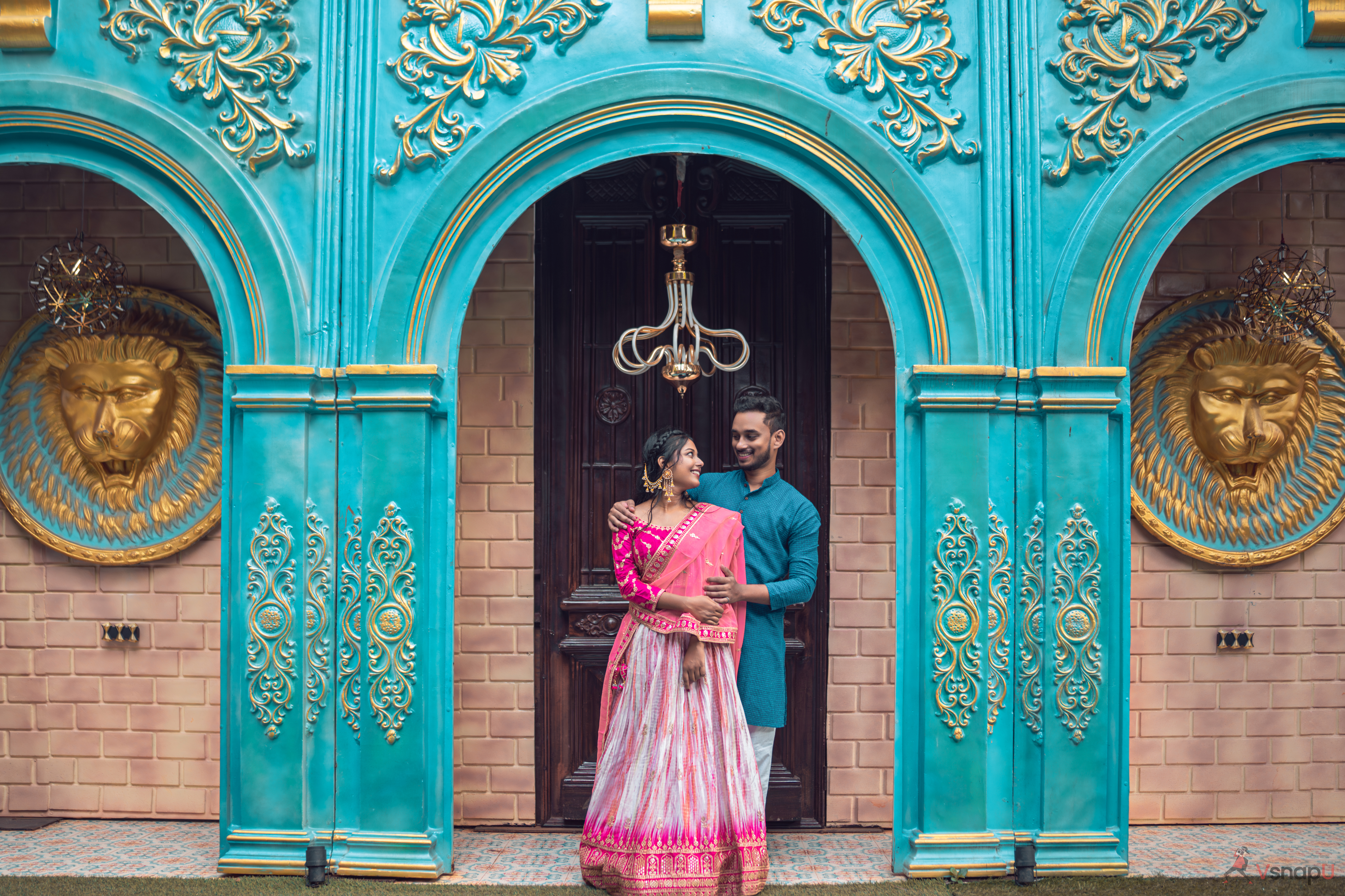 A romantic scene as the couple stands close, sharing a moment before grand gates.